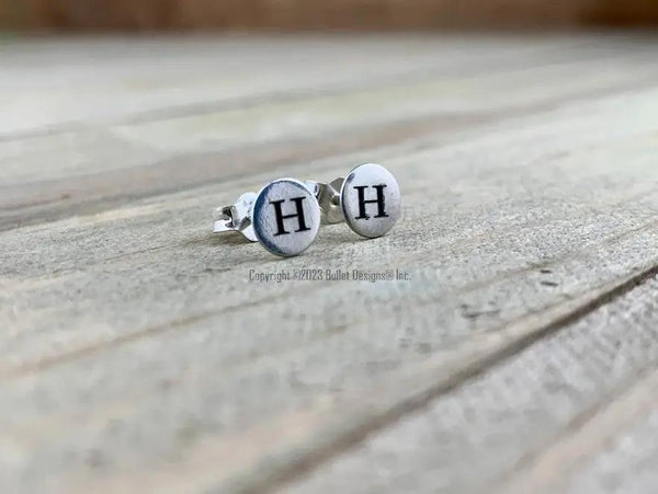 Custom initial engraved tiny sterling silver stud earrings with dark laser engraving featuring the letter 'H'. Personalized jewelry for gifting or daily wear.